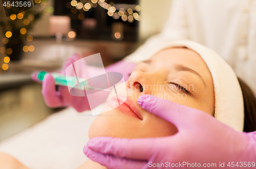 Image of beautician doing beauty injection to woman lips