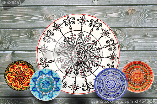 Image of Set of decorative ceramic plates hand painted dot pattern with acrylic paints on a gray wooden background. Copy space.