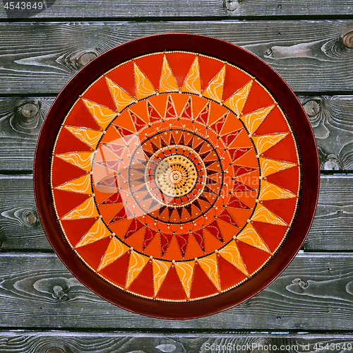 Image of Decorative ceramic plate, hand painted dot pattern with acrylic paints on a gray wooden background. A square photo. Closeup.