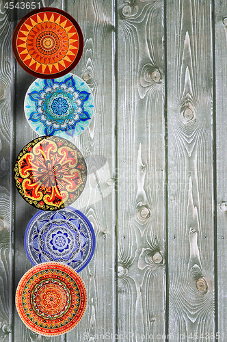 Image of Vertical Set of decorative ceramic plates hand painted dot pattern with acrylic paints on a gray wooden background. Copy space.