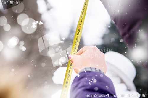 Image of young people measuring the height of finished snowman