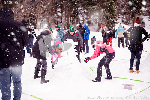 Image of group of young people making a snowman