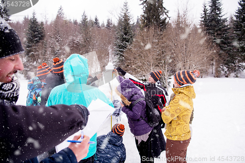 Image of young people measuring the height of finished snowman