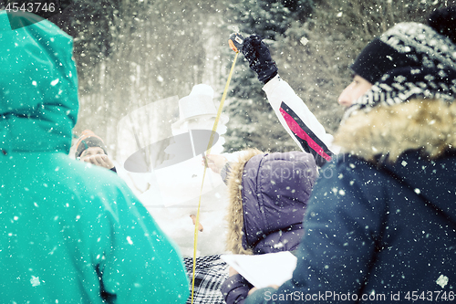 Image of young people measuring the height of finished snowman