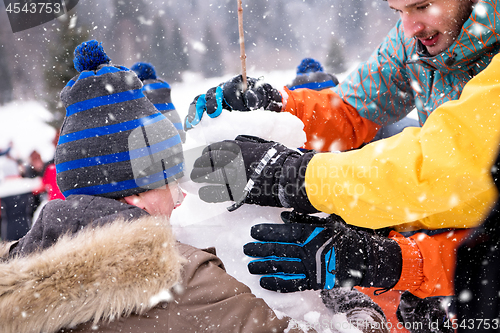 Image of group of young people making a snowman