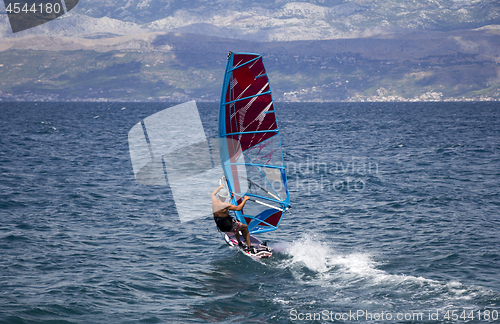 Image of Young windsurfer in the waves in the sea