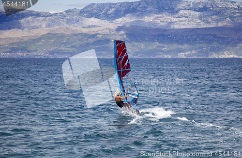 Image of Young windsurfer in the waves in the sea