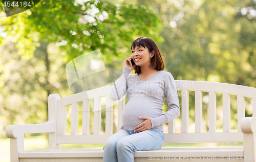 Image of pregnant asian woman calling on smartphone at park