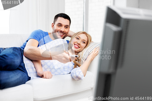 Image of happy smiling couple watching tv at home