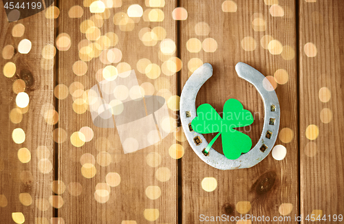 Image of horseshoe with shamrock on wooden background