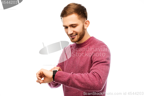 Image of smiling young man checking time on wristwatch