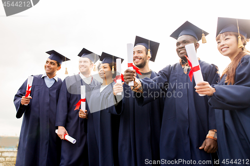 Image of happy students in mortar boards with diplomas