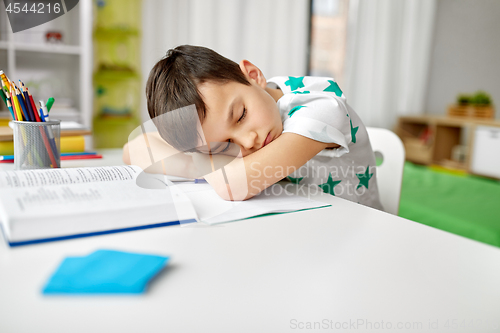 Image of tired student boy sleeping on table at home