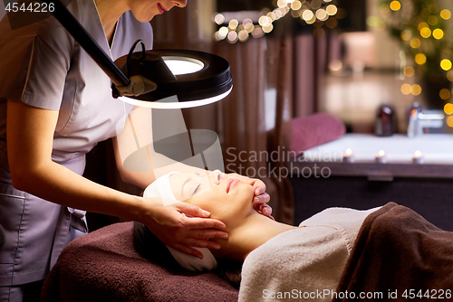 Image of beautician doing face massage to woman at spa