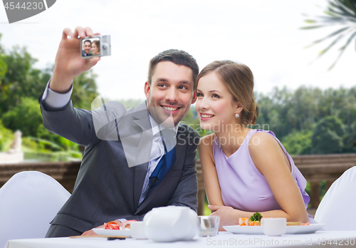 Image of happy couple taking selfie at sushi restaurant