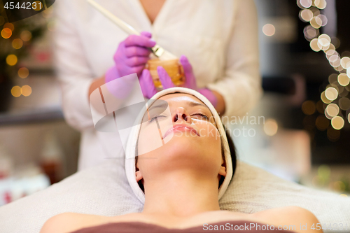 Image of beautician applying facial mask to woman at spa