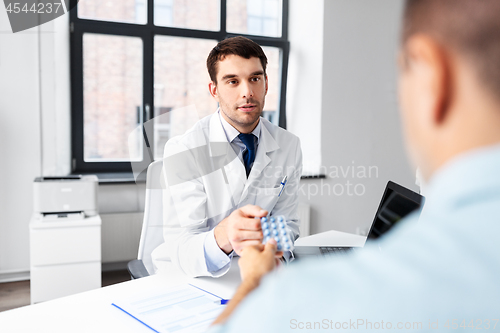 Image of doctor giving medicine to male patient at hospital