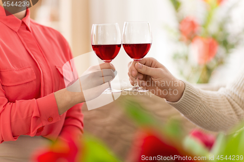 Image of hands of couple with red wine glasses toasting 