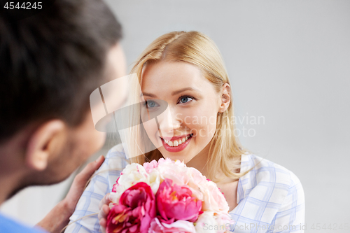 Image of happy couple with flowers at home