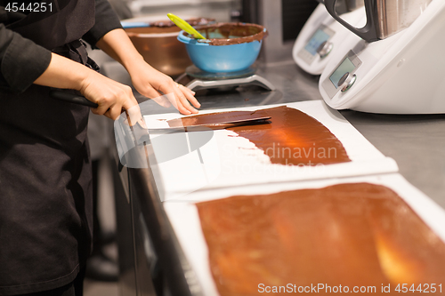 Image of confectioner makes chocolate dessert at sweet-shop