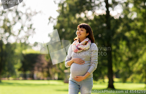 Image of happy pregnant asian woman walking at park