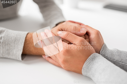 Image of close up of young woman holding senior man hands