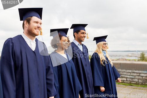 Image of happy students or bachelors in mortar boards