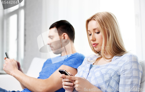 Image of couple with smartphones at home