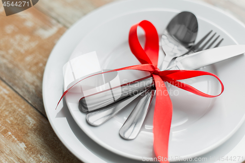 Image of close up of cutlery tied with red ribbon on plates