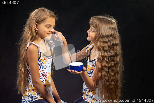 Image of Girl puts cream on her sister\'s nose