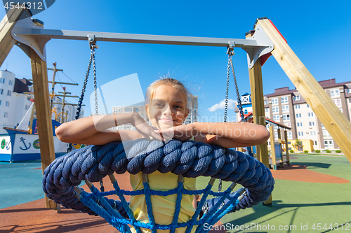 Image of Girl riding a round hanging swing in the playground