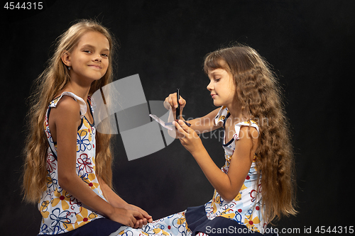 Image of A girl is applying powder to a brush; another girl is looking into the frame with pleasure