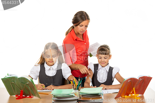 Image of The teacher helps schoolgirls in the lesson, prompting how to solve the problem