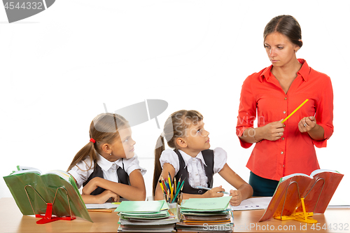 Image of Children at their desks look at the angry teacher with fear