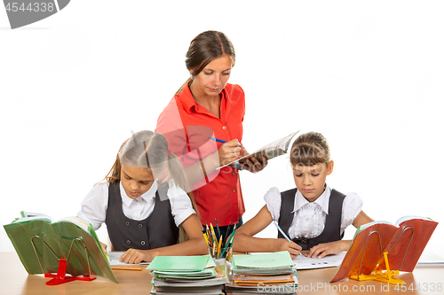 Image of The teacher checks how students cope with the assignment and notes the progress in the diary