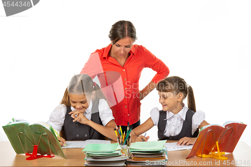 Image of Teacher and student look in the notebook of another student, where something funny