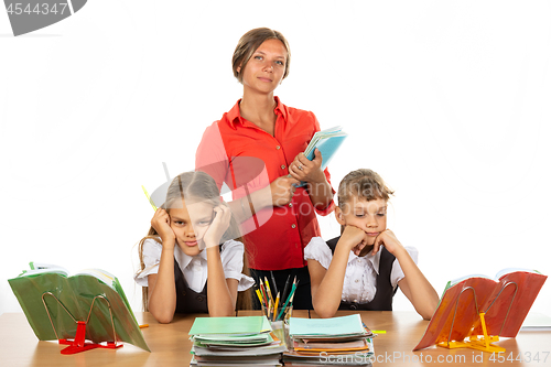 Image of Bored schoolgirls at a desk, in the background a teacher with notebooks