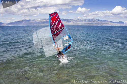 Image of Young windsurfer in the waves in the sea