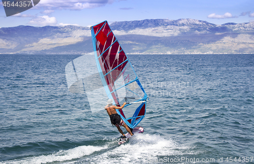 Image of Young windsurfer in the waves in the sea