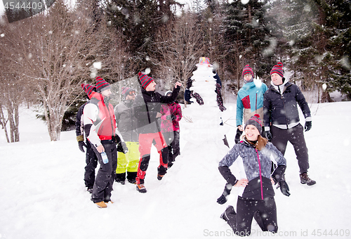 Image of group portait of young people posing with snowman