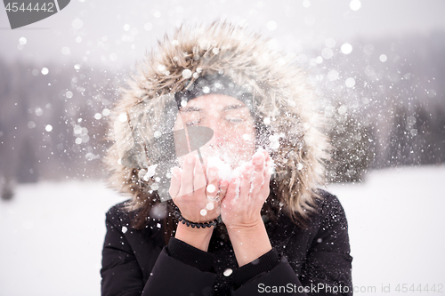 Image of young woman blowing snow on snowy day