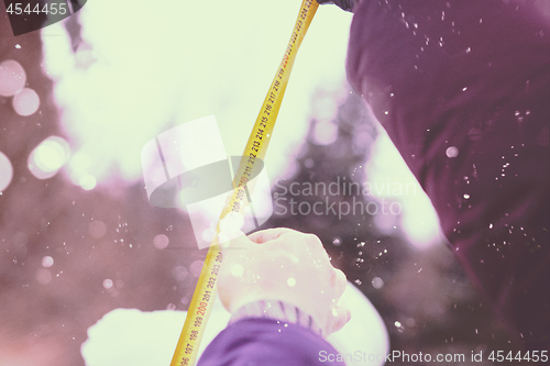 Image of young people measuring the height of finished snowman