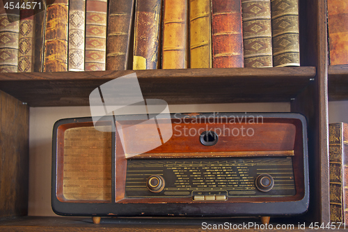 Image of Old vintage radio on the wooden shelf with books
