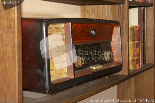 Image of Old vintage radio on the wooden shelf with books