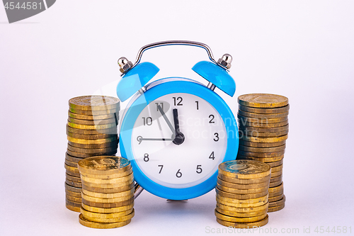 Image of Clock and stacks of coins close-up