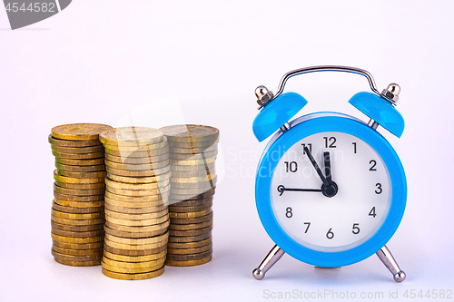 Image of Clock and stacks of coins are close by, close-up