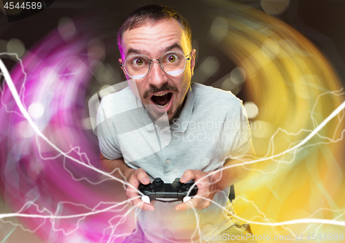 Image of Enthusiastic gamer. Joyful young man holding a video game controller