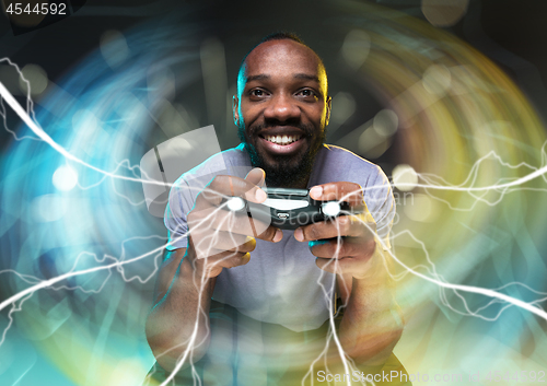 Image of Enthusiastic gamer. Joyful young man holding a video game controller