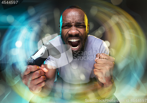 Image of Enthusiastic gamer. Joyful young man holding a video game controller