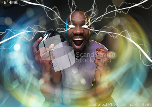 Image of Enthusiastic gamer. Joyful young man holding a video game controller